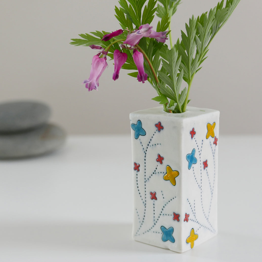 Square bud vase with blue, yellow, and teal flower design.